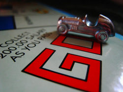 Image of metal car token on game board op top of the printed word GO